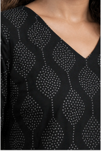 Black long-sleeve top with white geometric pattern on a blurred background